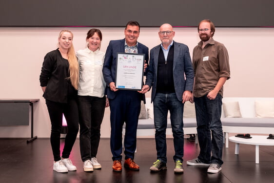 Landesverkehrsminister Winfried Hermann überreicht Vertretern des Heilbronner Landratsamts die Urkunde über die Auszeichnung mit der AGKF-Qualitätsstufe. Von links nach rechts: Vivien Mittelmeier, Nicole Rost, Dirk Schäfer, Leiter Amt für Mobilität und Nahverkehr des Landratsamts, Minister Winfried Hermann und Rolf Epple. Foto: Lencinas/AGFK-BW